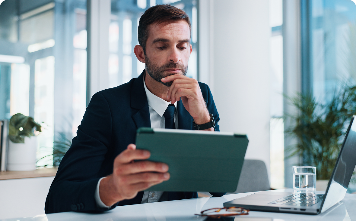 Man in suit using tablet at desk.