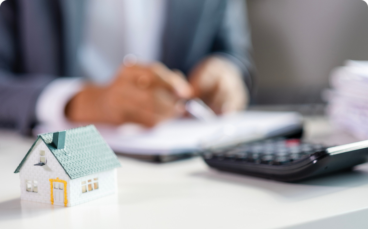 Miniature house and person writing, blurred background.