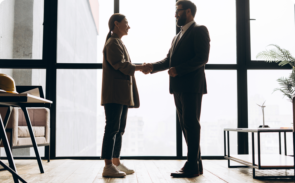 Two people shaking hands in office.